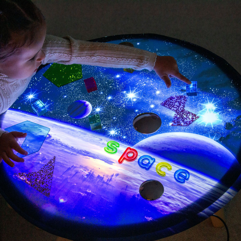 Child playing with a space-themed play mat on a light-up round light panel