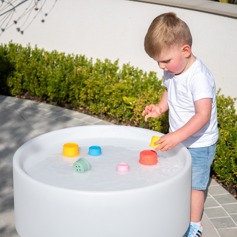Child playing with colourful silicone toys in a round sensory water table.