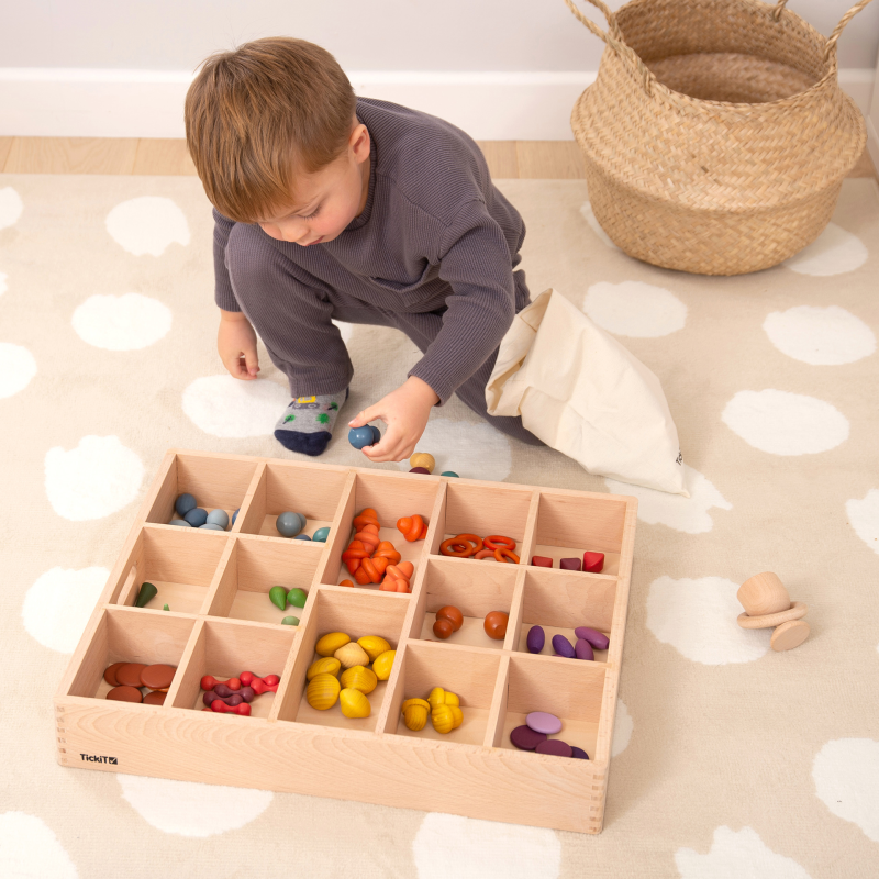 Child playing with a wooden tray toy set on a patterned floor