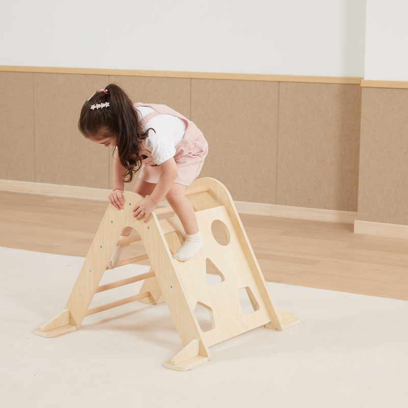 Child playing on a wooden climbing toy indoors