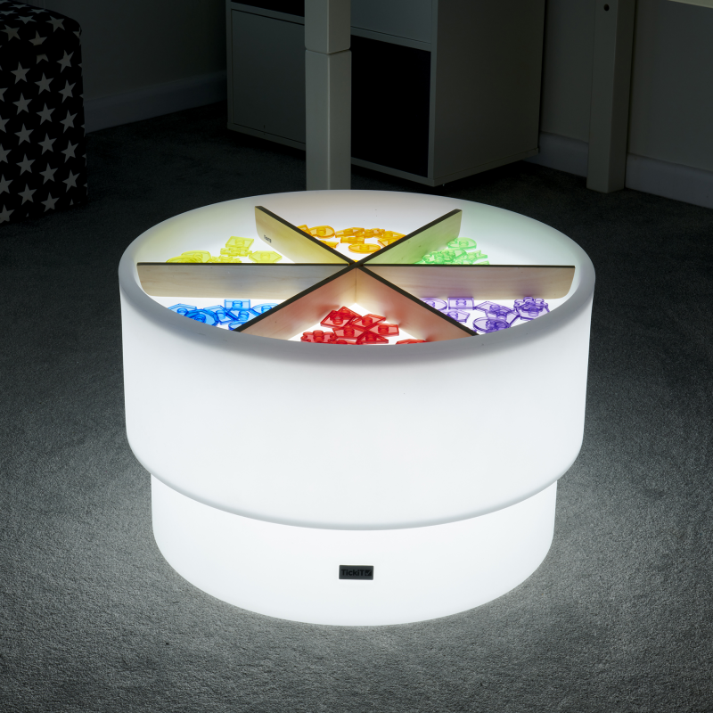 Round LED discovery table with colourful interior lights on a dark floor.