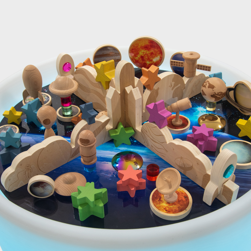 Wooden toy set with planets, stars, and space-themed elements on a space play mat