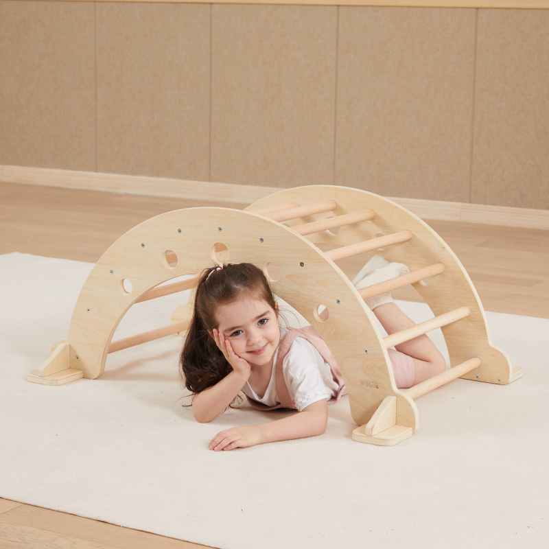 Child playing with a wooden climbing toy on a beige floor.