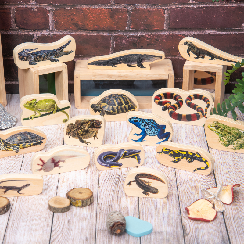 Set of wooden animal figures on a wooden surface with a brick wall background