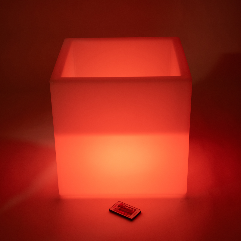 Red illuminated light cube with a remote control on a red background