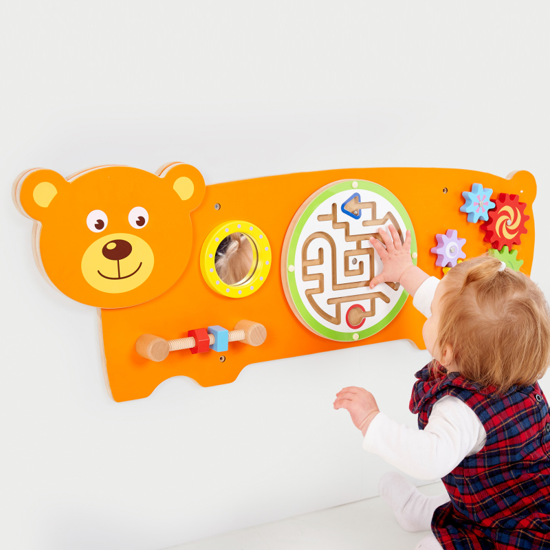 Child interacting with a colourful educational toy shaped like a bear on a white background
