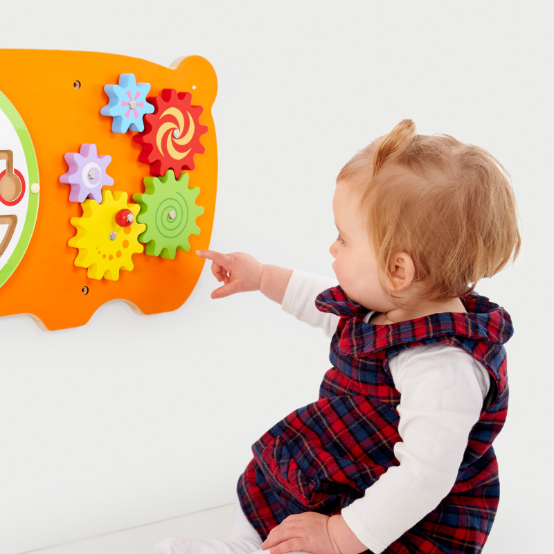 Child interacting with a colourful educational toy featuring gears and shapes.