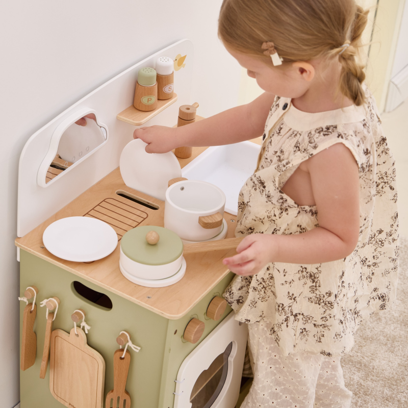 Child playing with a wooden toy kitchen set