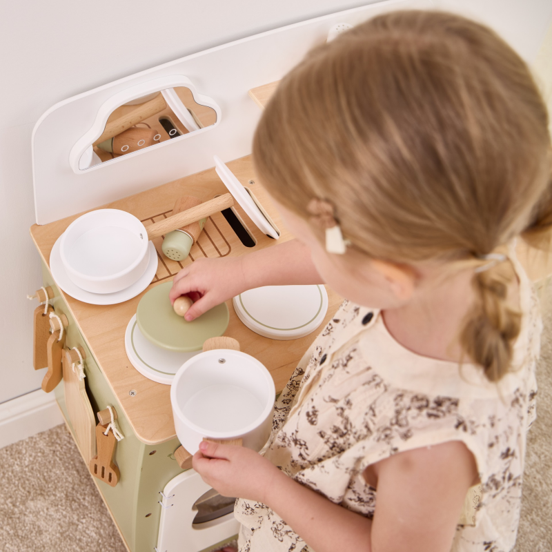 Child playing with a wooden toy kitchen set
