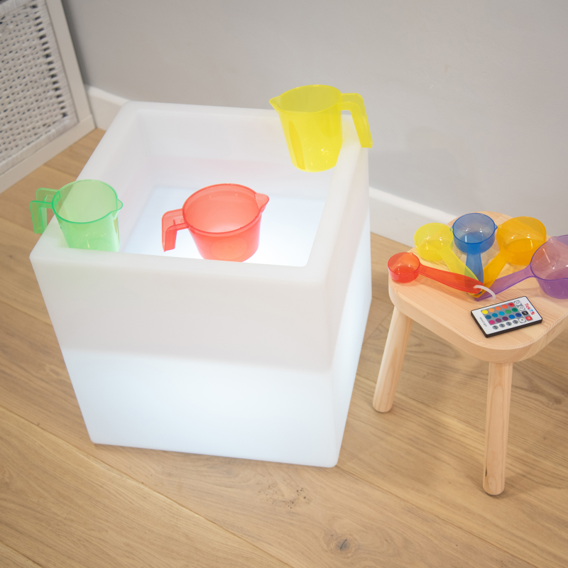 Colorful children's play items including cups and shovels on a wooden floor.
