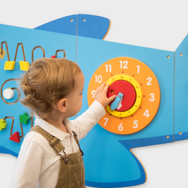 Child interacting with a colourful educational wall panel featuring numbers and shapes.