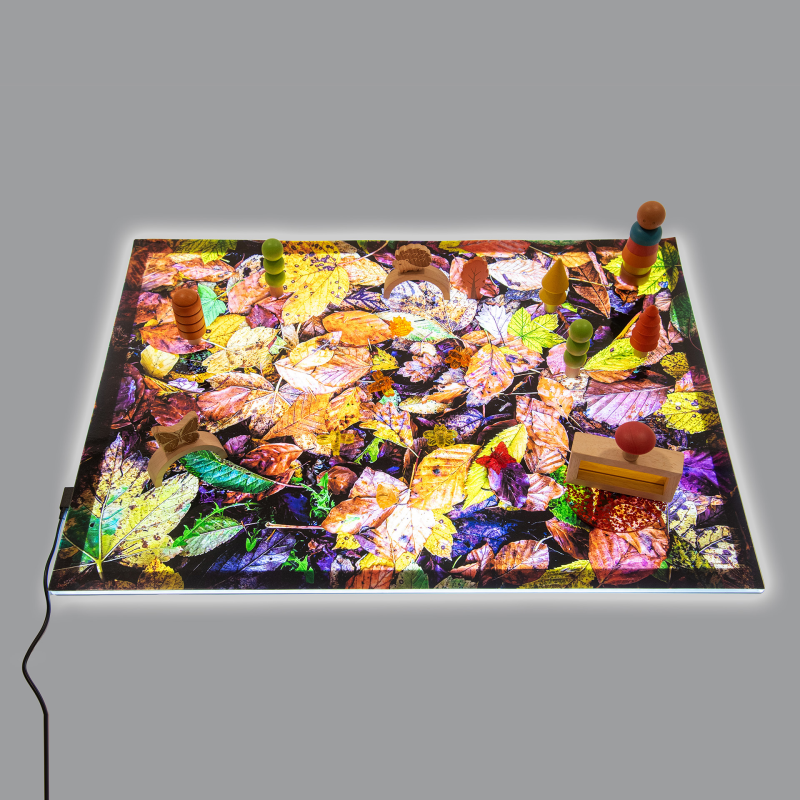 Colorful leaf-patterned mat on a light panel with small figurines on a gray background
