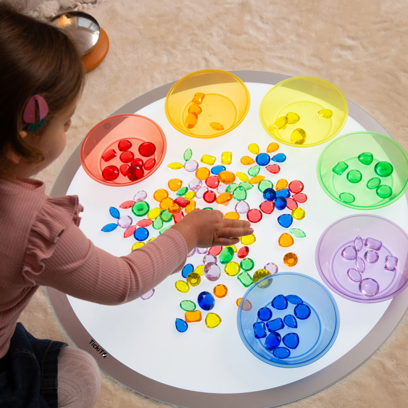 Child playing with a colorful sorting toy on a light surface