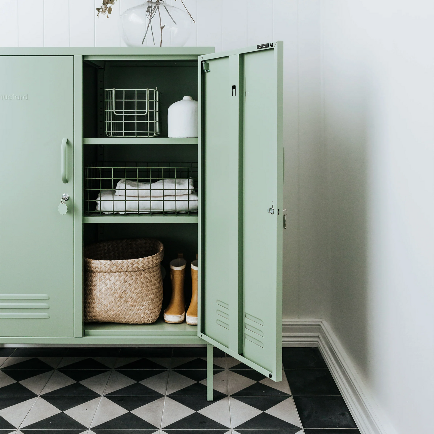 Green cabinet with open doors on a black and white checkered floor