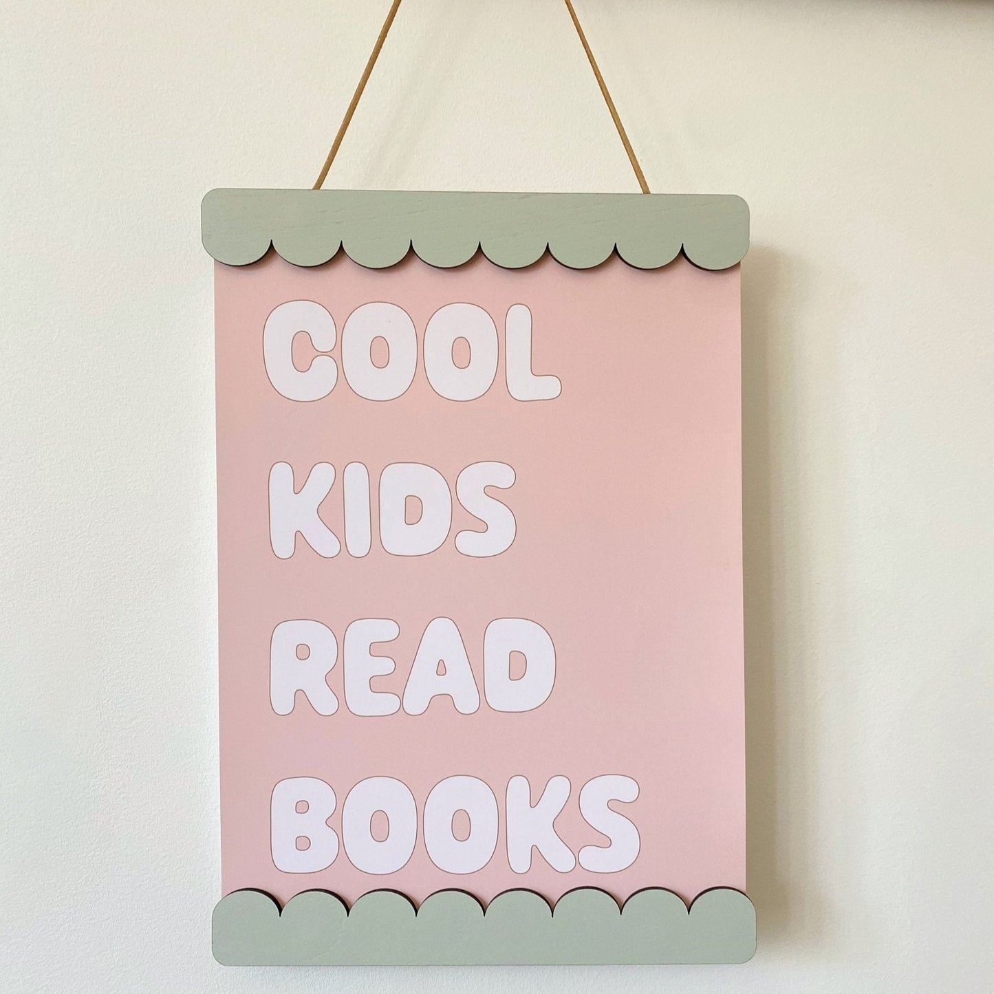Pink sign with 'Cool kids read books' text on a white wall