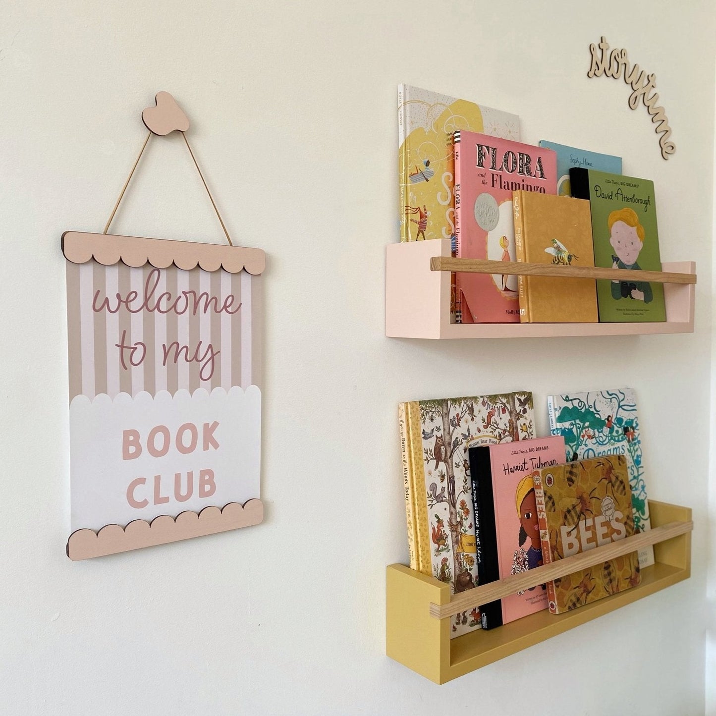 Wooden bookshelf with books and a decorative sign on a white wall.