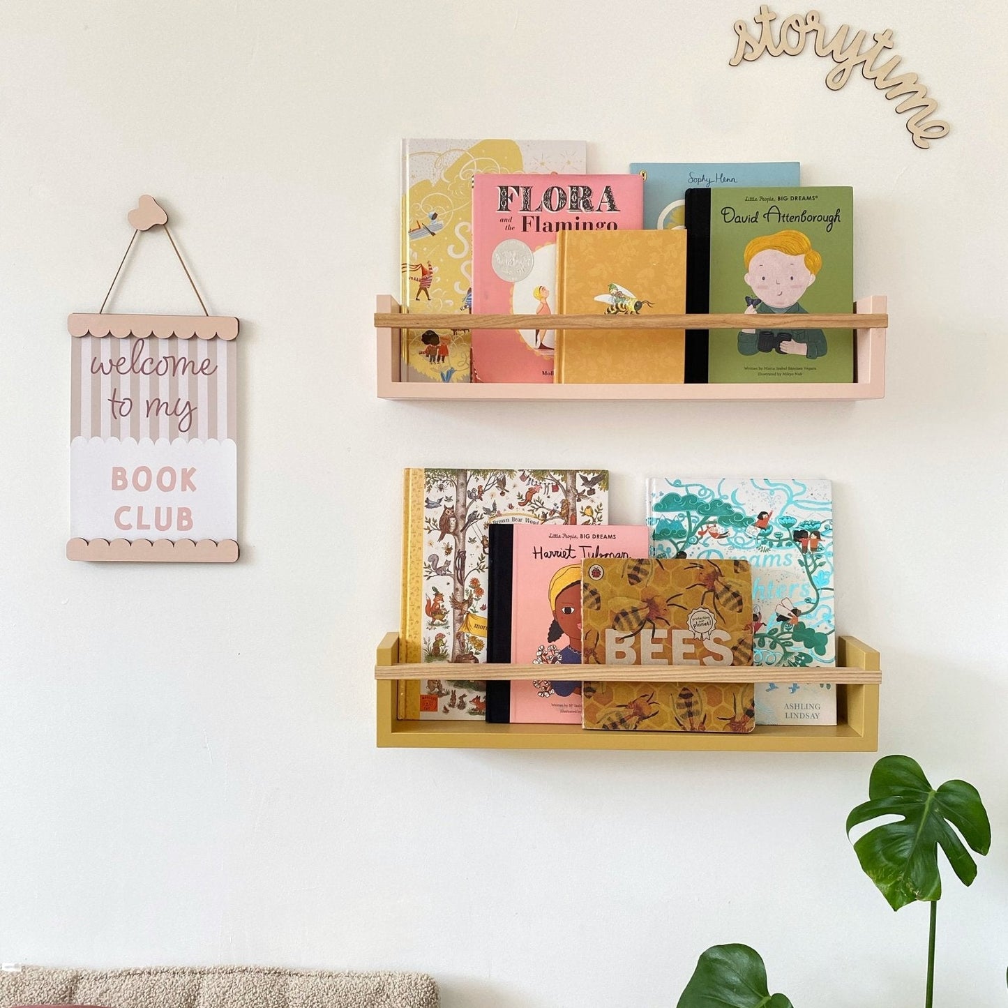 Wooden bookshelf with children's books on a white wall, featuring decorative signs.
