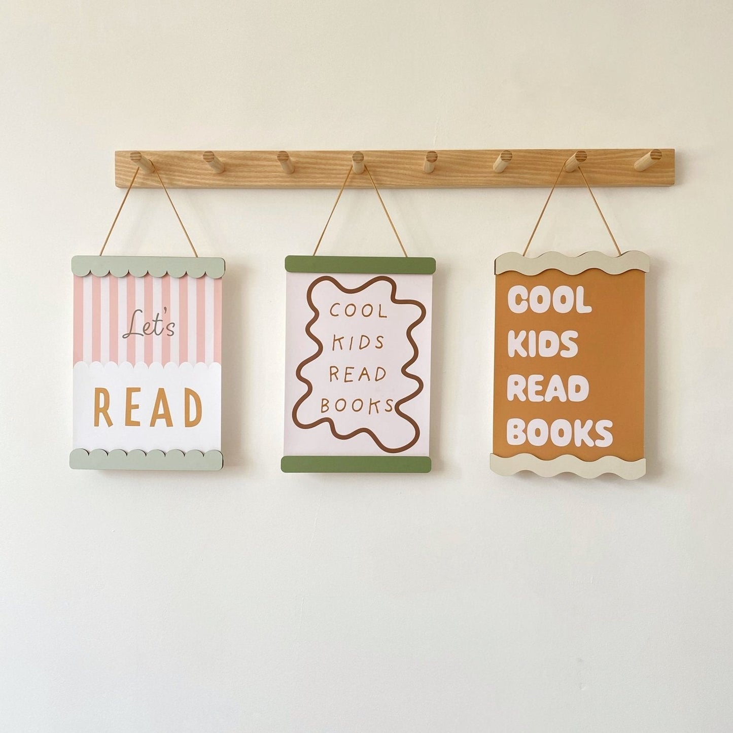 Three motivational signs for children hanging on a wooden rod against a white wall.