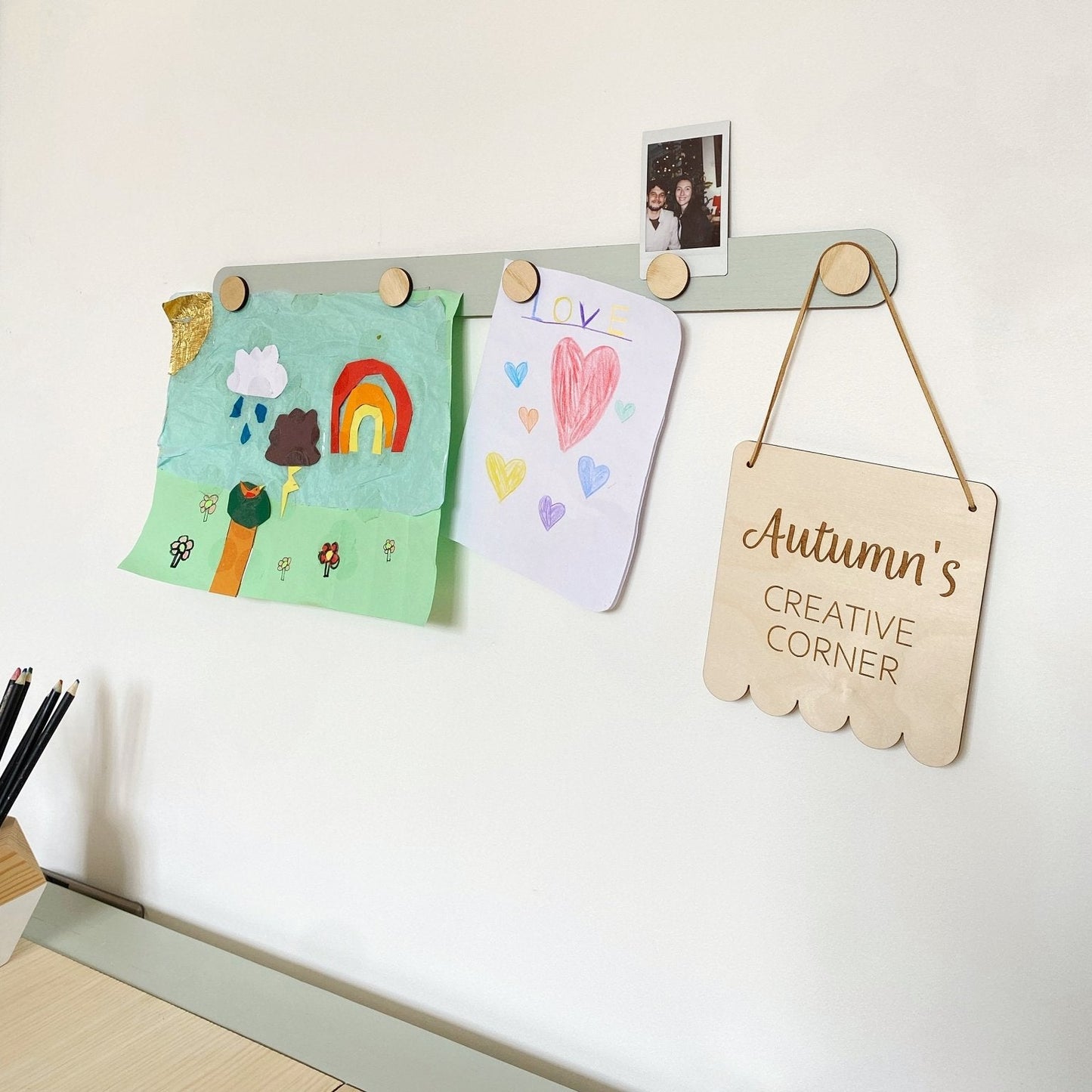 Children's art displayed on a magnetic board with a sign reading 'Autumn's Creative Corner'.