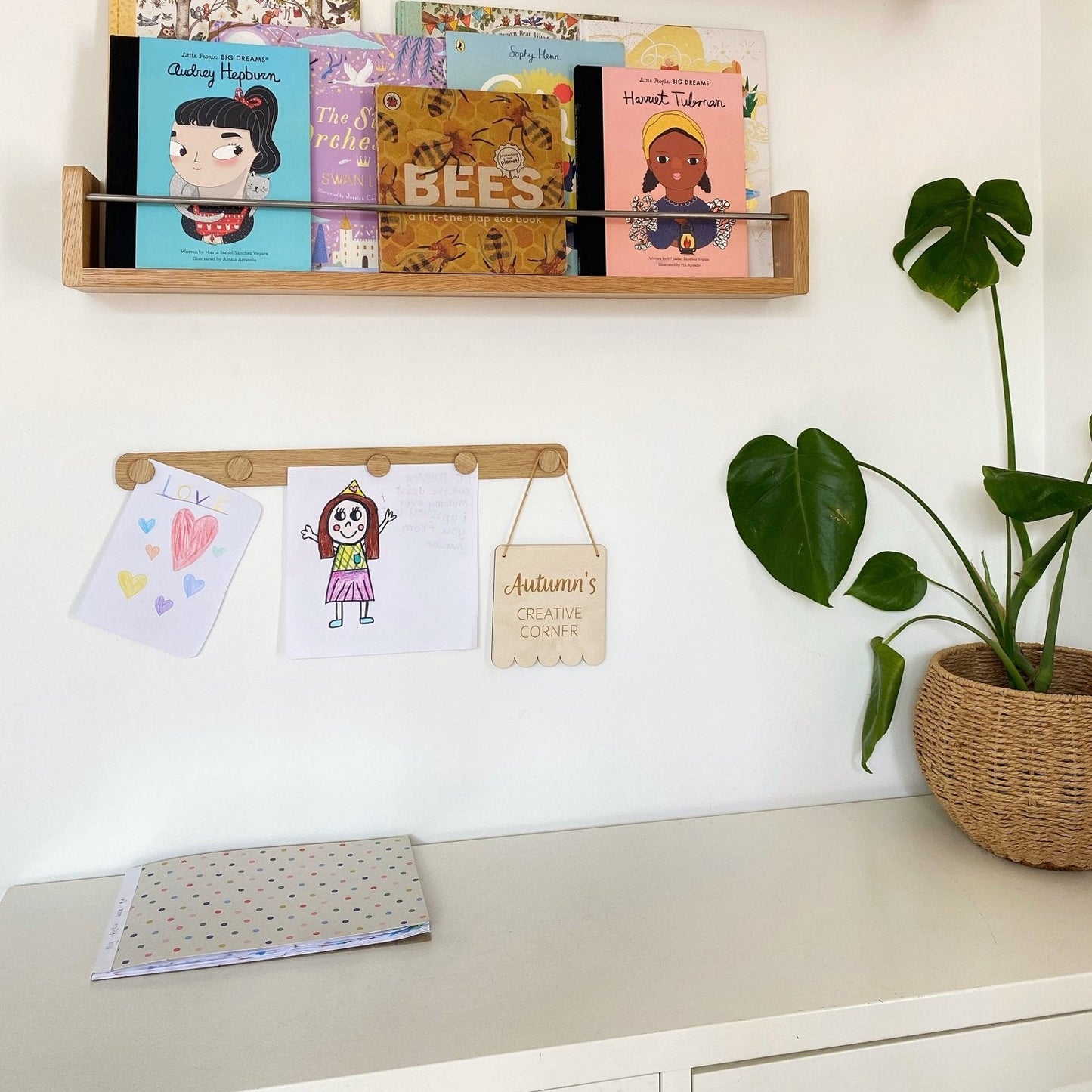 Wooden wall shelves with books and cards on a white wall.