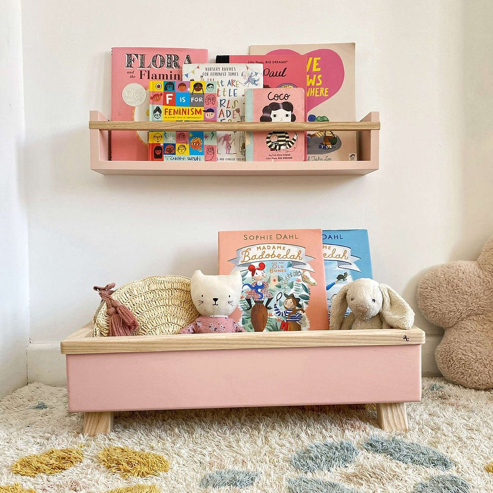 Children's bookshelf with books and toys on a carpeted floor.