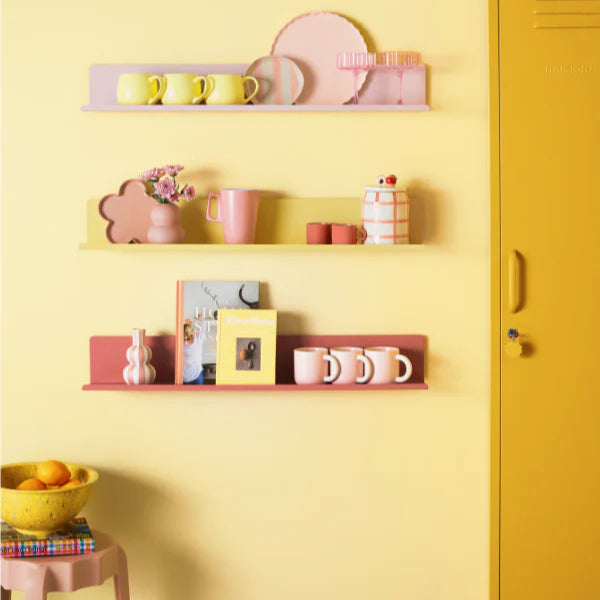 Shelves with decorative items against a yellow wall with a yellow locker.