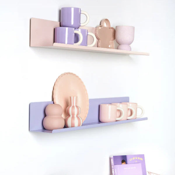 Decorative shelves with pastel-colored mugs, plates, and a vase on a white wall.