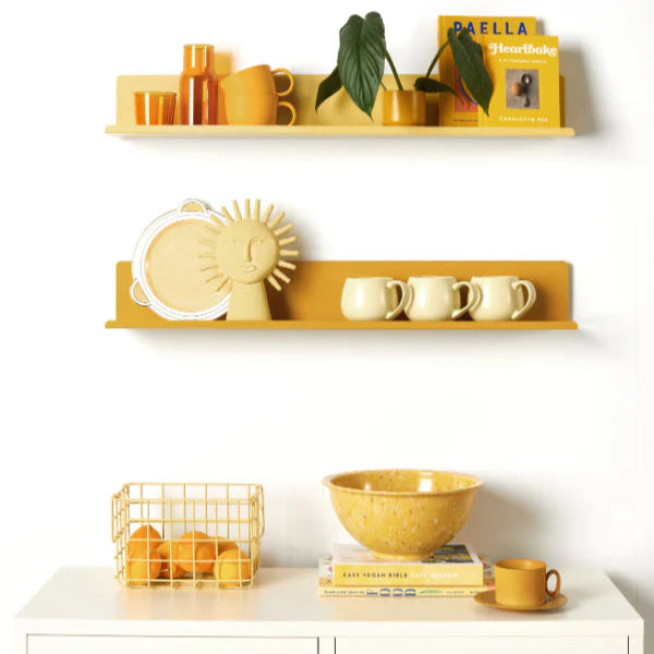 Yellow shelves with decorative items against a white wall