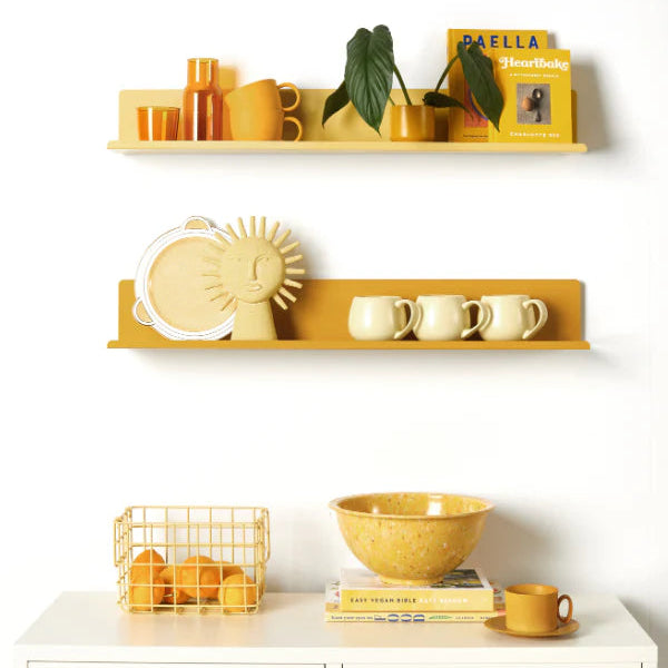 Yellow shelves with decorative items against a white wall