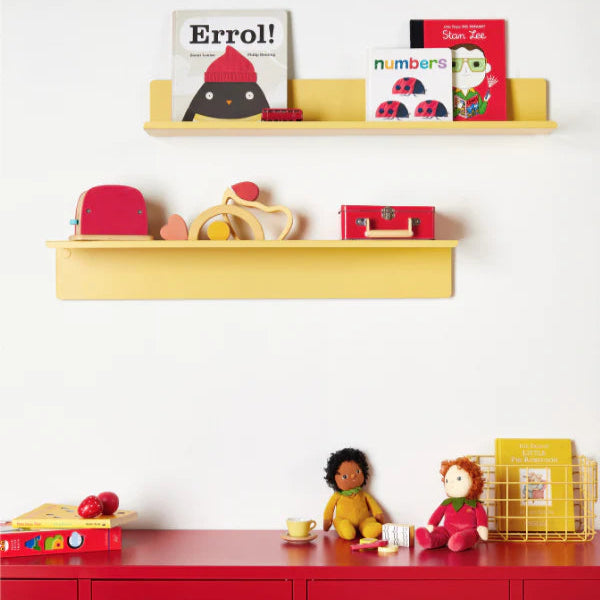 Yellow shelves with toys and books above red lockers against a white wall