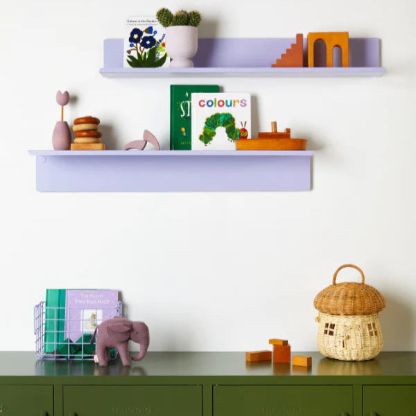 Children's room with purple shelves and green cabinets, featuring toys and books.