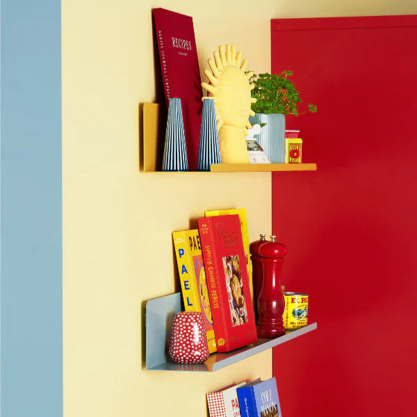 Colorful shelves against a red, yellow, and blue wall with books, mugs, and decorative items.