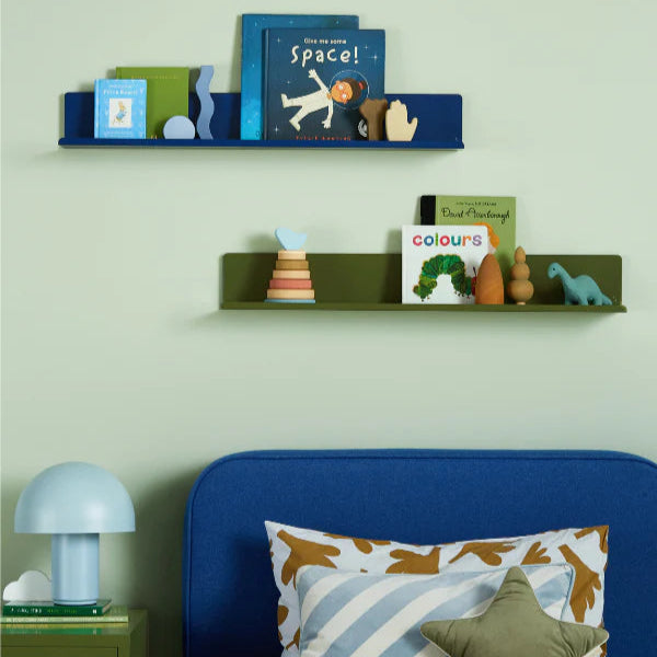 Children's room with shelves displaying books and toys against a light green wall.