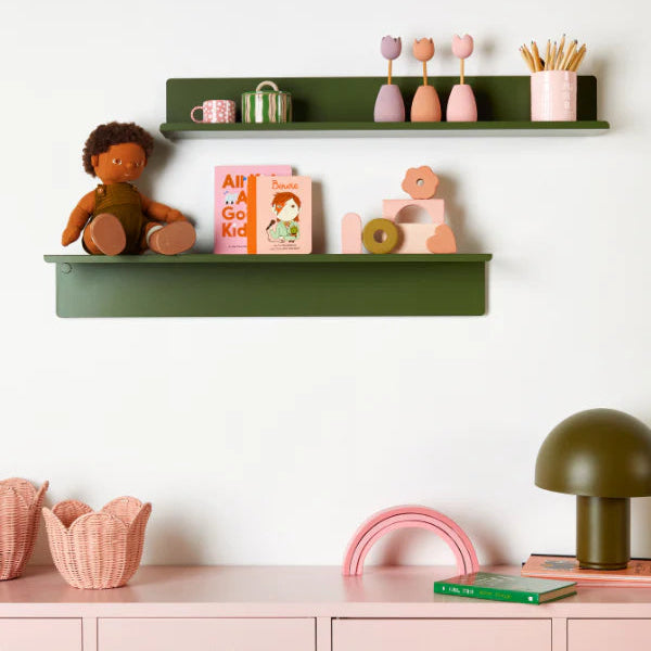 Children's room with green shelves and pink locker, featuring books and toys.