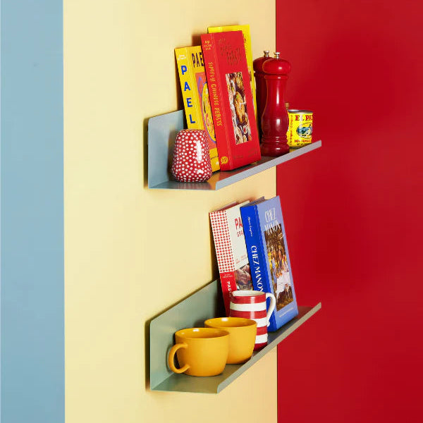 Colorful shelves against a red, yellow, and blue wall with books, mugs, and decorative items.