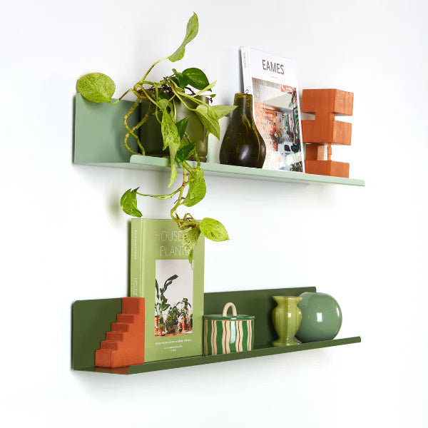 Decorative shelves with green and orange items on a white wall