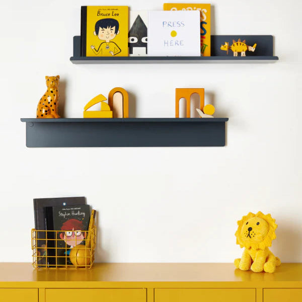 Shelves with books and toys on a white wall above yellow lockers.