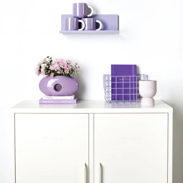 Lilac shelf on wall with white cabinet and light purple decor