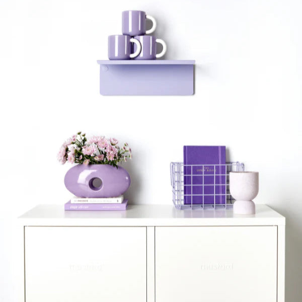Lilac shelf on wall with white cabinet and light purple decor