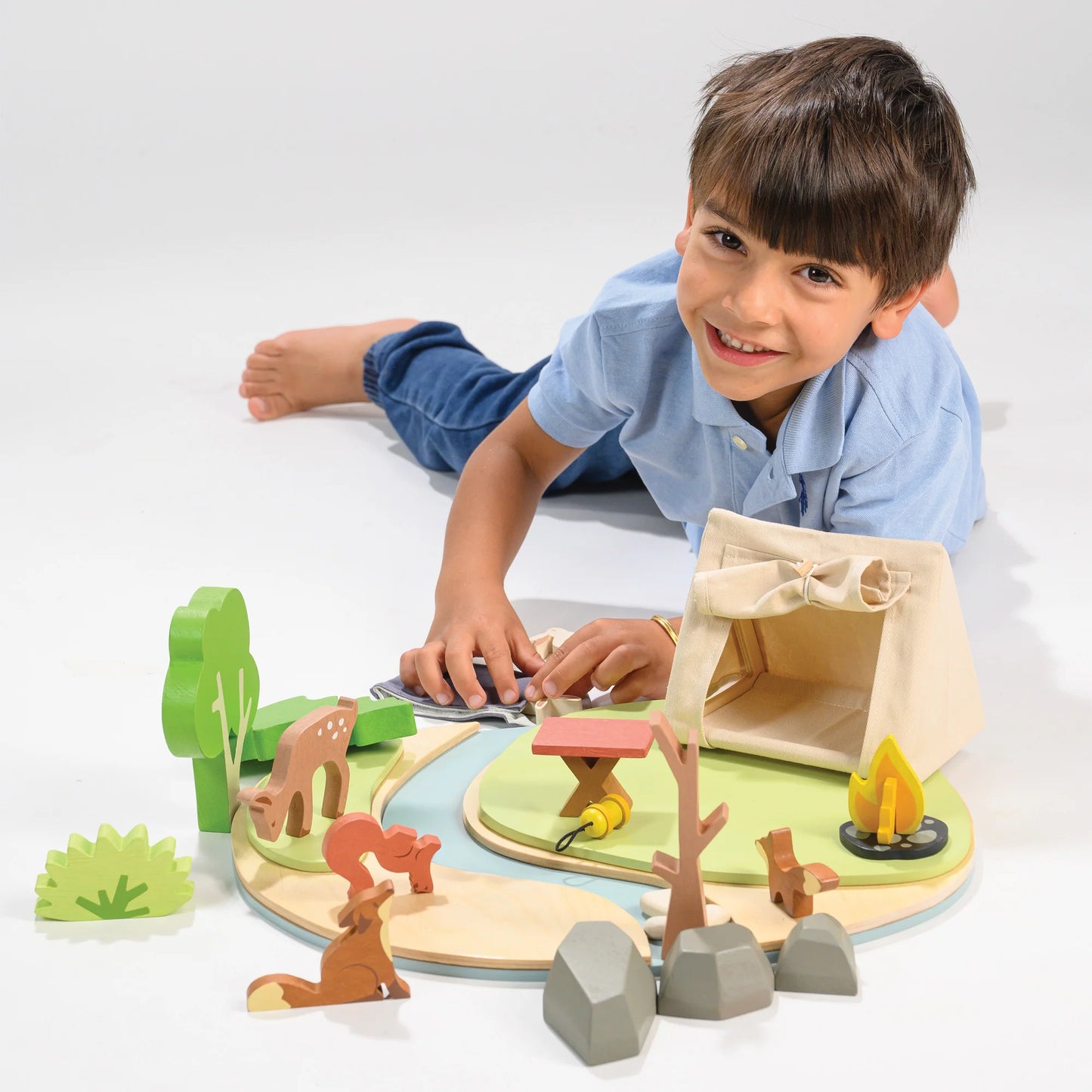 Child playing with a wooden toy set on a white surface