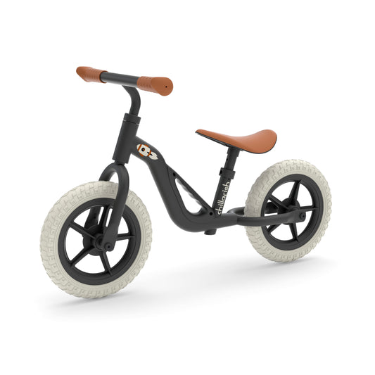 Children's balance bike with black frame and brown handlebar and seat on a white background