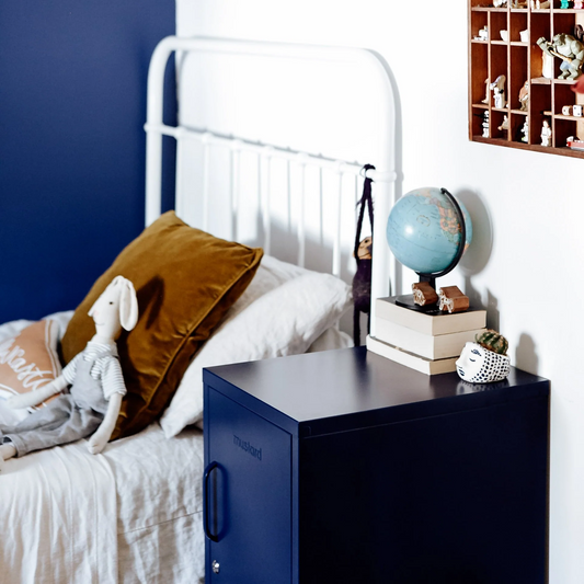Bedroom with a white bed, brown pillow, blue nightstand, and wooden shelf with decorative items.