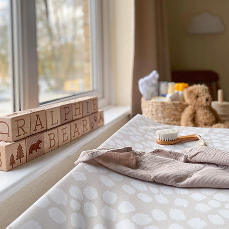 Children's room with wooden blocks, teddy bear, and basket by a window.