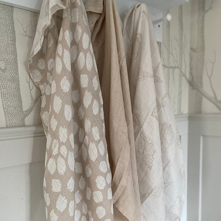 Beige patterned towel hanging on a rack against a white wall.