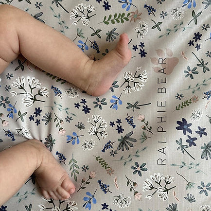 Baby legs on a floral-patterned blanket with 'Ralphie Bear' branding.