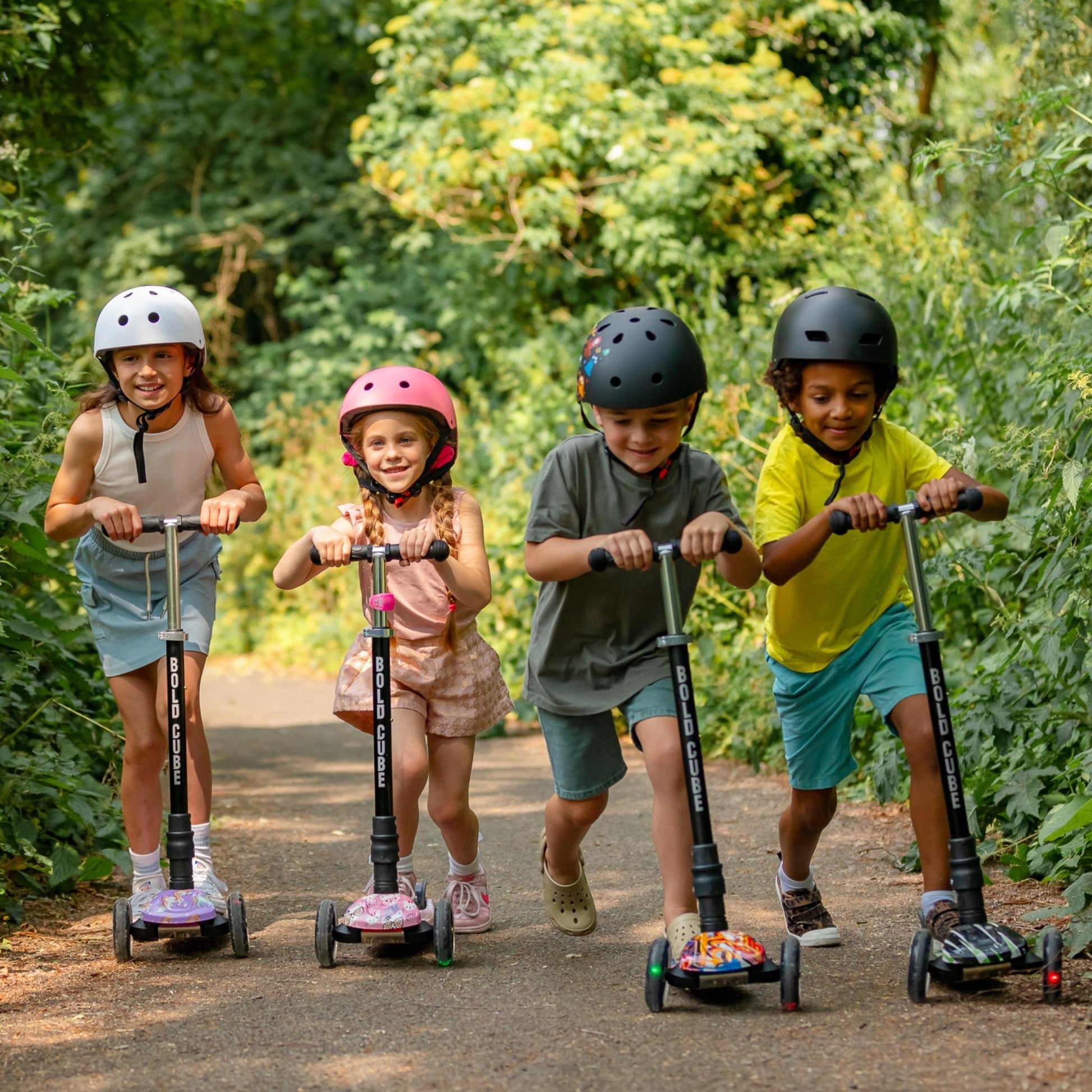 Four children riding scooters on a path surrounded by greenery