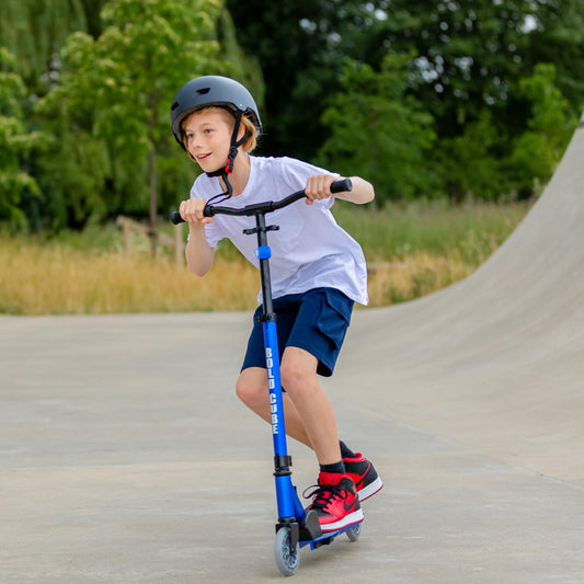 Child riding a scooter on a ramp with greenery in the background