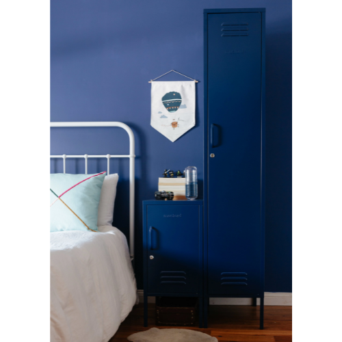 Blue locker against a blue wall in a bedroom with a bed and decorative items.