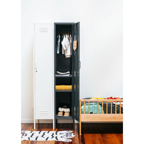Black locker with clothes and shoes inside, next to a white locker and wooden bed in a room.