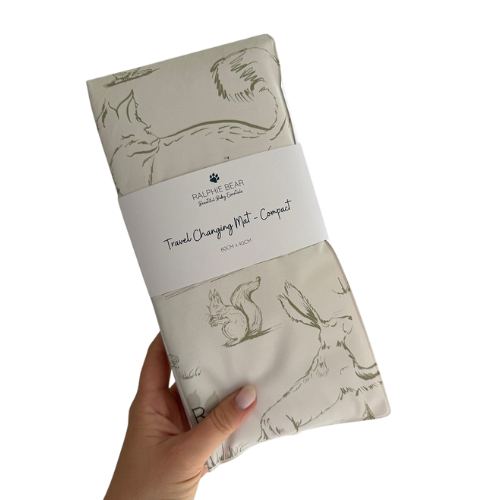 Travel changing mat with animal illustrations held by a hand on a white background